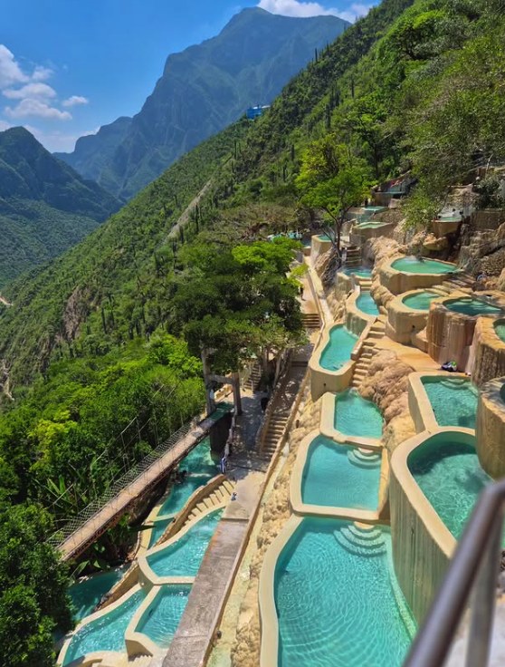 Grutas Tolantongo thermal pools running down the canyon wall with the mountains of Hidalgo behind them
