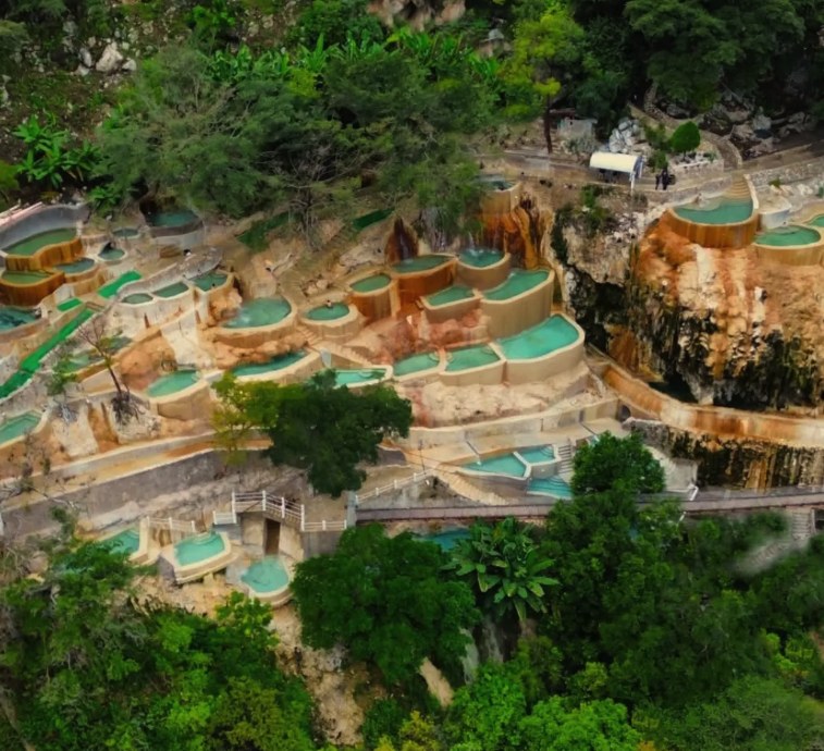 The terraced thermal pools of Para&iacute;so Escondido at Grutas Tolantongo from above, jade-green water stepped down ochre travertine terraces