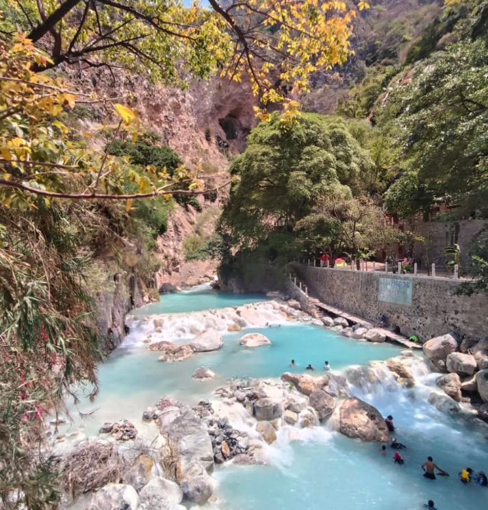 The milky turquoise thermal river at Grutas Tolantongo running between white boulders in the canyon