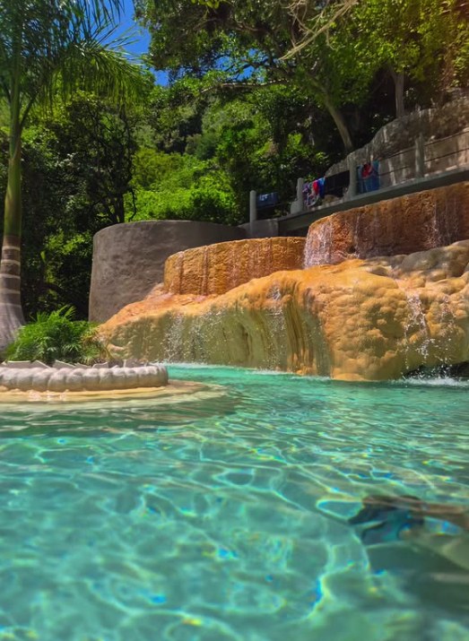 Water spilling over ochre travertine into a turquoise pool